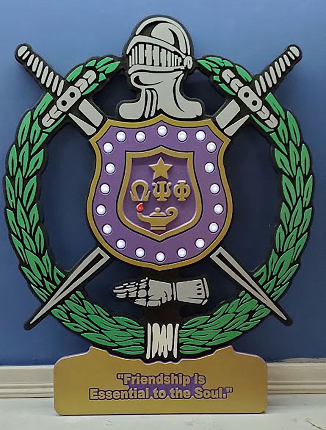alt= "Omega Psi Phi Fraternity - Carved Retro Shield with a personalized plaque. It is provided with LED lighted pearls and flame. It comes in four sizes (16", 24" 36" and 48" high."